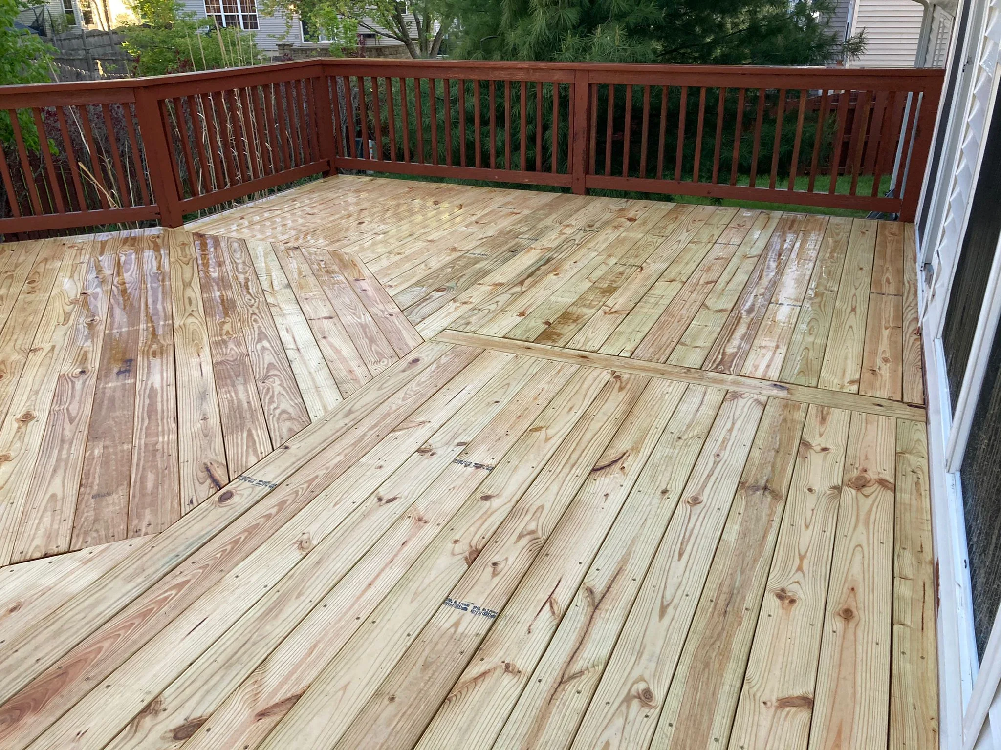 Freshly cleaned light-wood deck in Champaign County — bright boards and dark railings after pressure washing